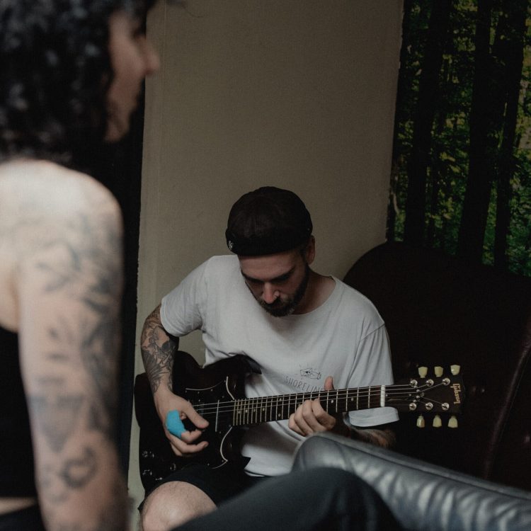 A member of Melonball preparing his guitar in the backstage area.
