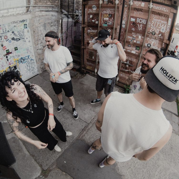 Five members of Melonball standing outsite in a circle moments before the show.