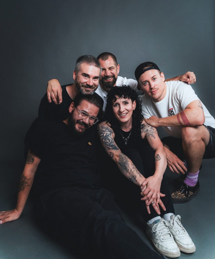 Melonball press pic 3 by Manuel Wieslhuber The five members of Melonball sitting or crouching on the floor smiling in the camera